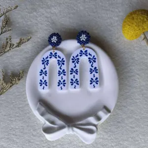 boucles d'oreilles IONE arche motif noeud bleu sur fond blanc puce bleu et blanche