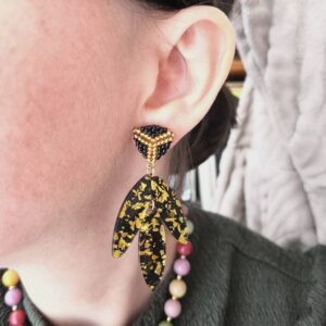 boucles d'oreilles Pénélope pendantes feuilles acrylique noires et dorées portées