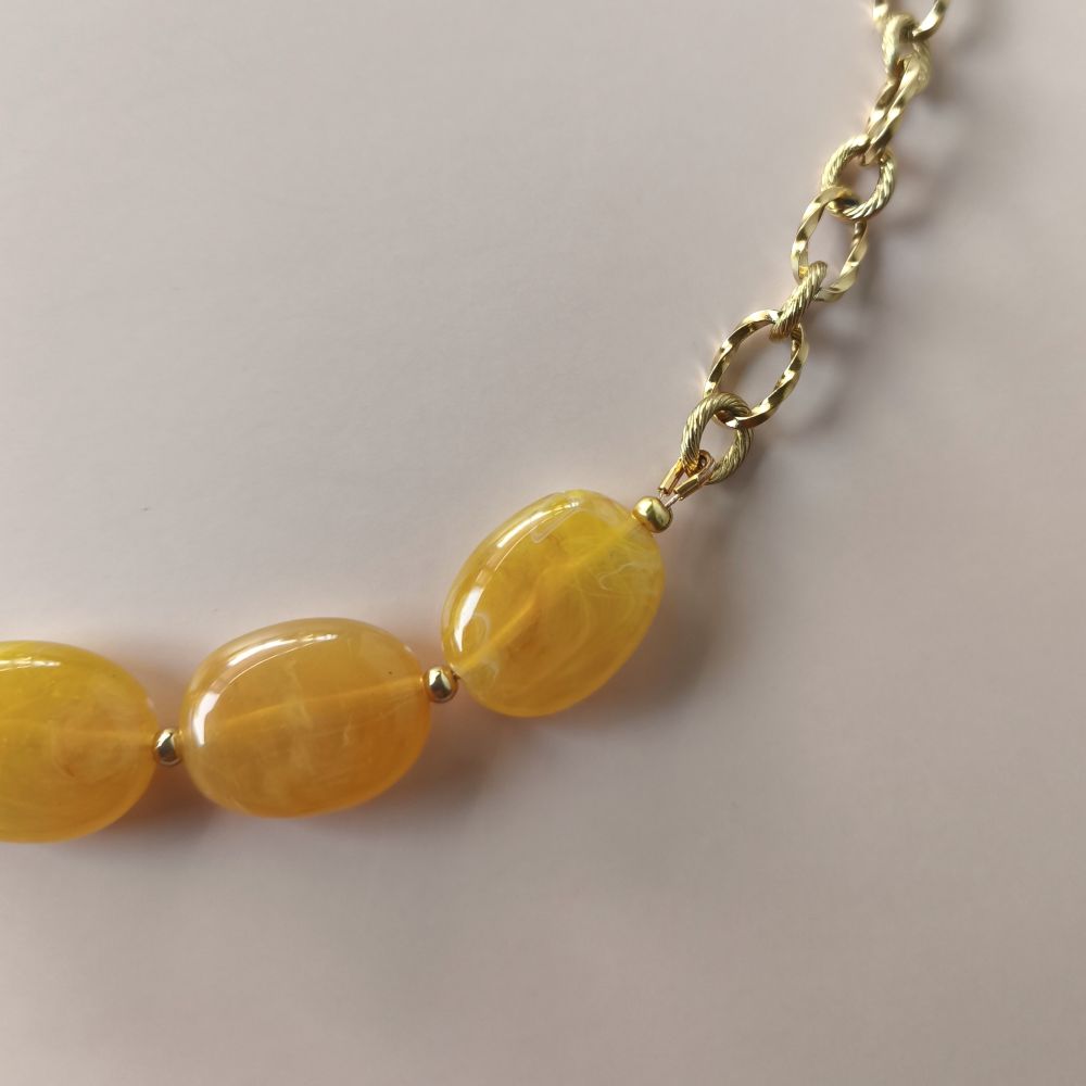 zoom sur le détail de la chaine et des perles marbrées ambre jaune